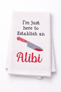 White towel with red knife graphic and text 'I'm just here to establish an alibi' on a white background