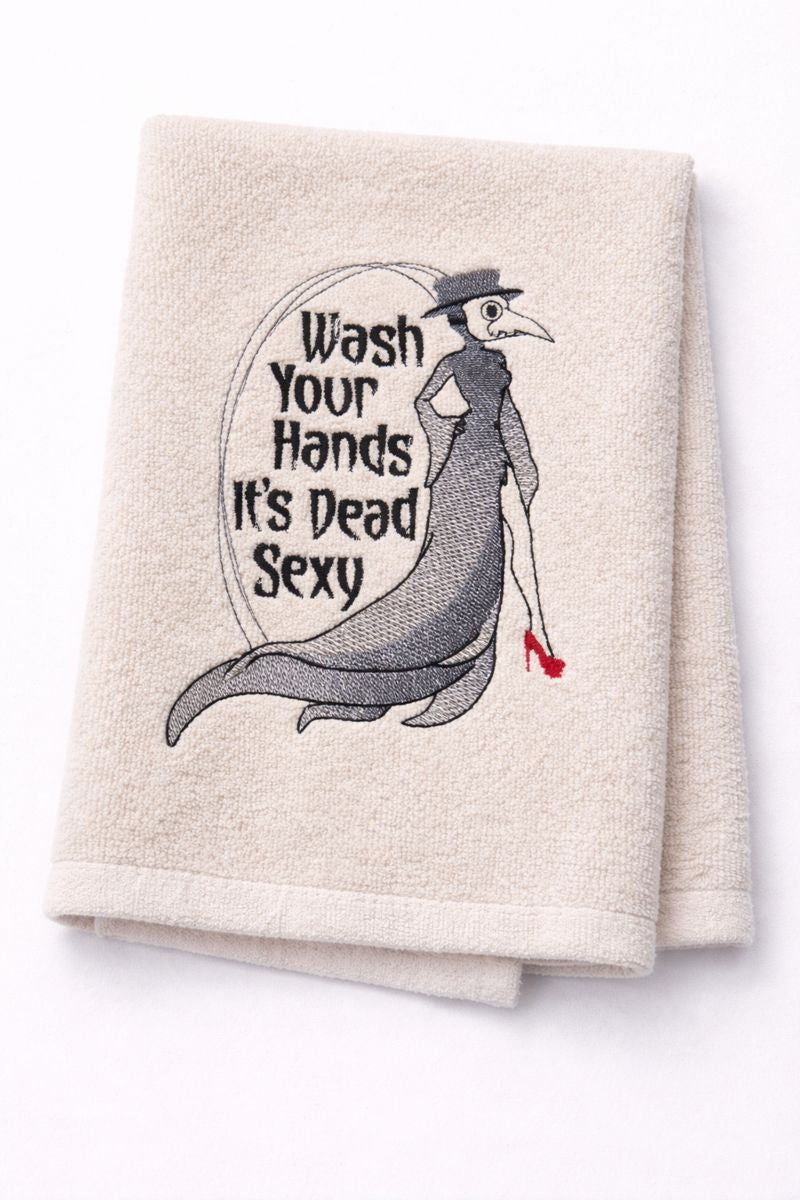Folded towel with a graphic of a plague doctor and text 'Wash Your Hands It's Dead Sexy' on a white background.